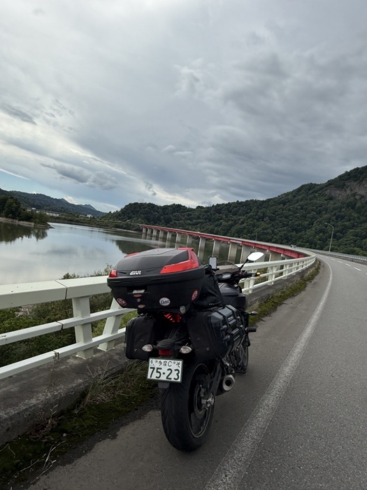 おびらしべ湖と赤い欄干の橋を背景にしたMT-07